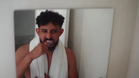 Bearded man brushing his teeth in bathroom mirror Stock Footage 336975040