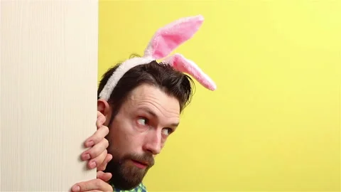 Bearded man in bunny ears  look out the wall and waving hand  happy easter Stock Footage 148226565