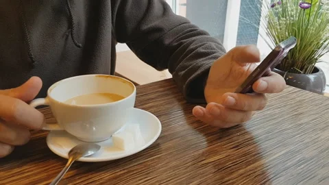 Bearded man in a cafe drinking coffee and talking on the phone. Stock Footage 97412255