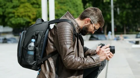 Bearded man with camera takes a video in the city street Stock Footage 107949889