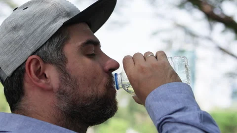 Bearded man in cap drinks water from bottle. Video stock 306647310