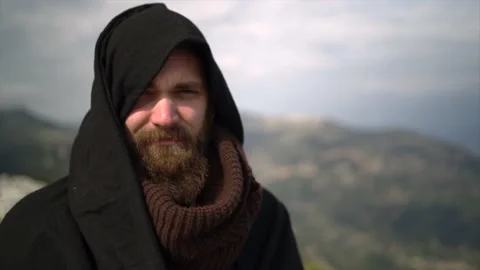 Bearded man with cape on top of mountain. Video stock 153313924