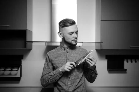 Bearded man checks the sharpness of the blade at the knife in his hands Foto stock