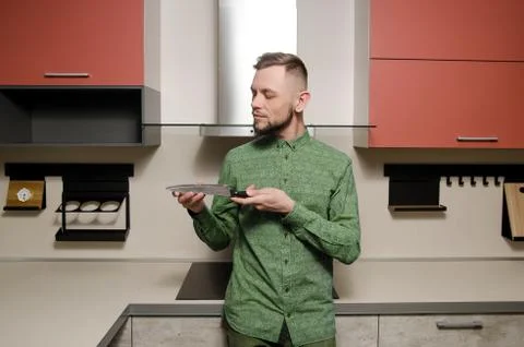 Bearded man checks the sharpness of the blade at the knife in his hands in th Foto stock