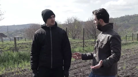 Bearded Man Cheering up a Sad Friend on a Sunny Spring Day in the Field Stock Footage 239654544