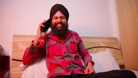 Bearded man chuckles while talking through smartphone Stock Footage 312381271