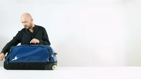 Bearded man collects things in a suitcase for travel Stock Footage 102866111