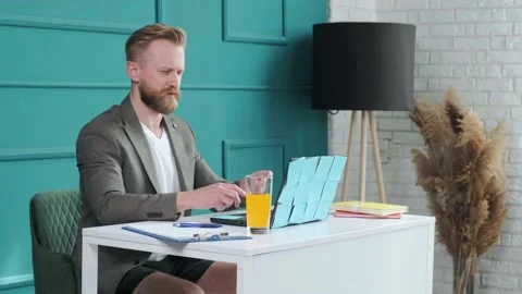 Bearded man comfortable at his desk, in underwear and jacket working remote. Stock Footage 154908028