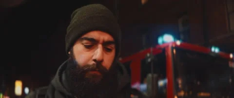 Bearded man concerned talking by phone with a fire truck in the background Stock Footage 203583676