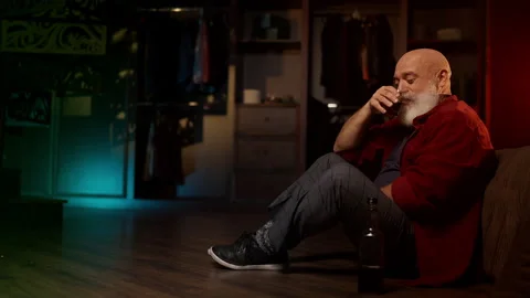 Bearded man copes with midlife crisis, drinking alcohol while sitting on floor Stock Footage 342520507