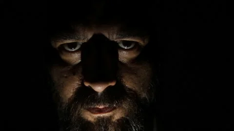 Bearded man in the dark looking at the camera. Low light in the dark. Video stock 157500855