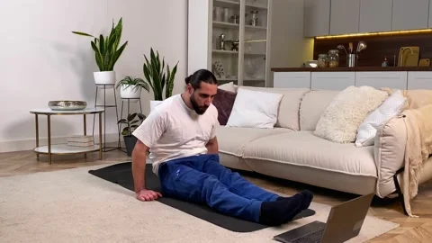 Bearded man doing candlestick exercise watching video tutorial indoors 動画素材 229567970