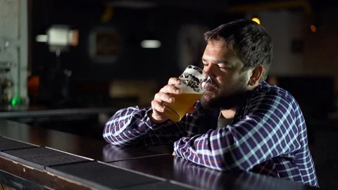 Bearded man drinking beer and enjoying a drink at the pub bar. Male guest tries Видео 96569771