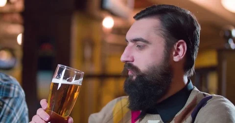 Bearded man drinking beer enjoying pub bar 4k video. Male guest tastes lager Stock Footage 71153044