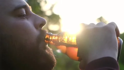 Bearded man drinking cold beer at sunset, slow motion 100 fps Stock Footage 108061059