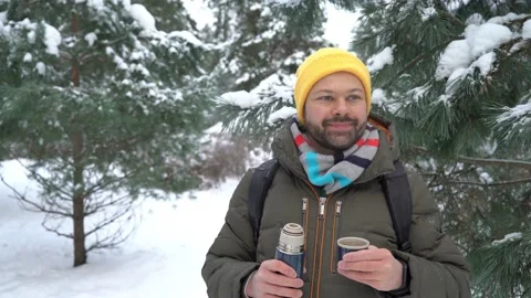 Bearded man drinking hot tea in winter forest Stock Footage 146479424