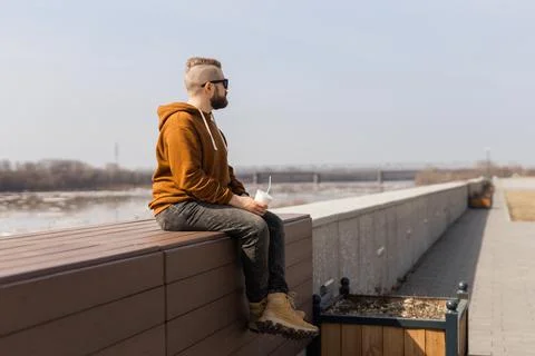Bearded man drinking a shake in spring promenade. Drinks take away and gen z or Foto stock