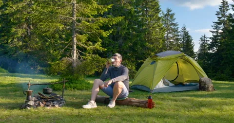 A bearded man is drinking tea near the fire Stock Footage 157113678