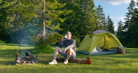 A bearded man is drinking tea near the fire Stock Footage 157183970