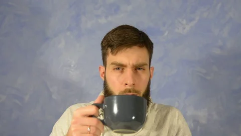A bearded man drinks from a cup and looks at the camera. Brutal bearded man 스톡 동영상 127912061