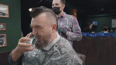 Bearded man drinks water while cutting and dyeing hair Stock Footage 144668656