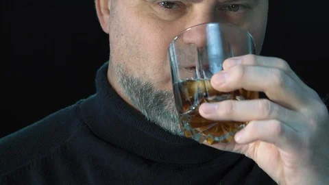 Bearded man drinks  whiskey with ice cubes.  Isolated on black background Video stock 124897857