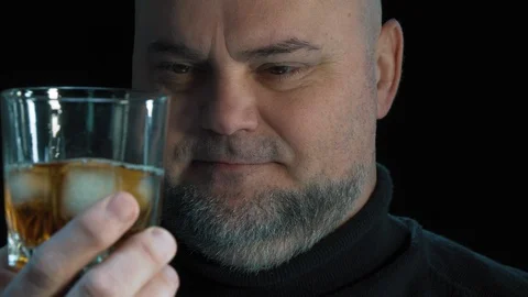 Bearded man drinks  whiskey with ice cubes.  Isolated on black background 스톡 동영상 124899766