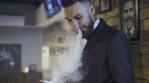 Bearded man with e-cigarette in interior vapes Stock Footage 56576652
