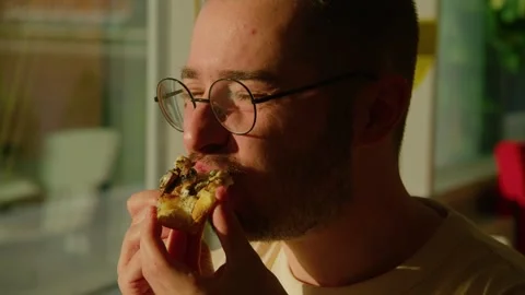 Bearded man eating a slice of pizza and enjoying it in a restaurant, close-up Stockbeeldmateriaal 244084972
