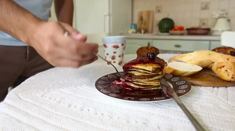 Bearded man eats with appetite Pancake in the kitchen Stock Footage