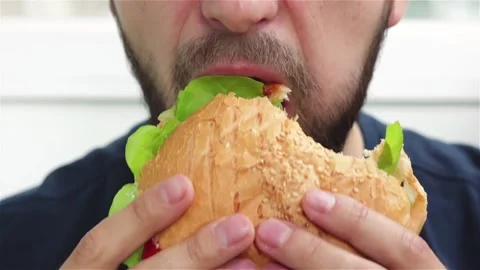 Bearded man eats delicious burger  soft focus close up Stock Footage 120058194