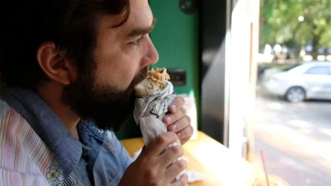 Bearded man eats fast food wrap Stock Footage 138878363