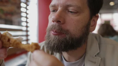 Bearded man eats fried chicken in fast food Видео 160545059
