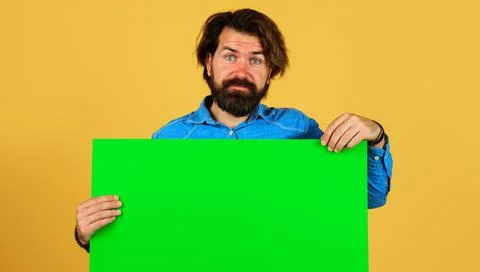 Bearded man with empty sign board. Smiling male with advertising banner. Spac Stock Photos