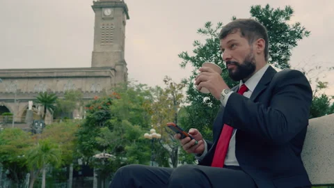 Bearded man in an expensive suit typing something on his phone while sitting on Stock Footage 218326601