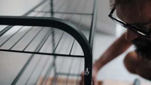 Bearded man in eyeglasses self assembling metallic shelf connect details shoes Stock Footage 233469570