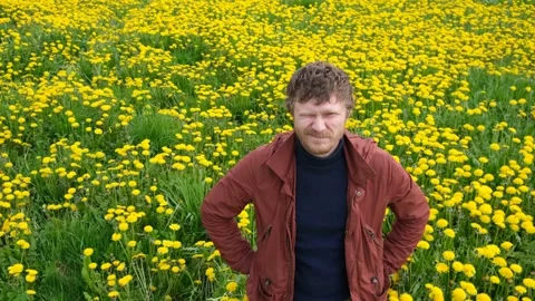 Bearded man in field of yellow dandelions looking at the camera, smiling Stock Footage 131614421