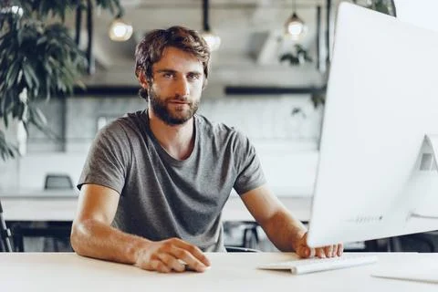 Bearded man freelancer using computer in a modern coworking place Stock Photos