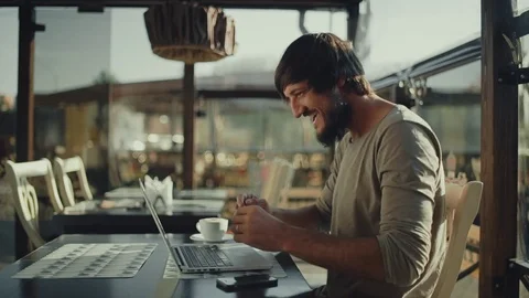 Bearded man freelancer very happy and rejoices sitting in front of laptop in Stock Footage 75802522