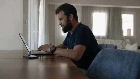 Bearded man freelancer works remotely at table at home Stock Footage 248981610