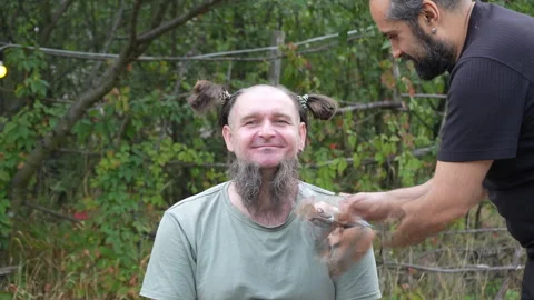 Bearded man with funny braids gets beard shaved outdoors Stock Footage 318219000