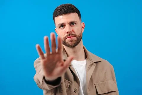 Bearded man gesturing stop with hand in front of blue background Stock Photos
