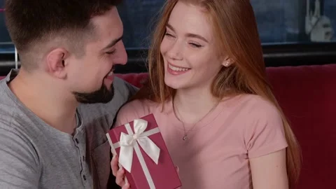 Bearded man is giving his ginger woman a present embracing her and smile Stock Footage 150138959
