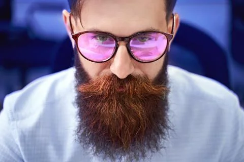 Bearded man in glasses with screen reflection working on computer in IT office Foto stock