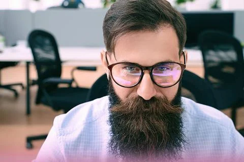 Bearded man in glasses with screen reflection working on computer in IT of... Stock Photos