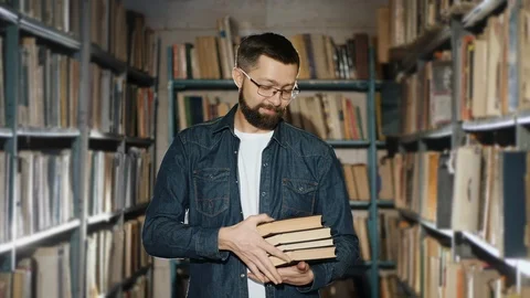 A bearded man in glasses suggests reading several books Stock Footage 124948596