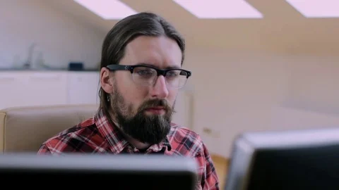 Bearded man in glasses working in office with 2 monitors Stock Footage 73178152
