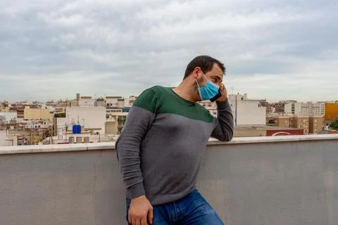 Bearded man in a gray and green sweater with a surgical mask to protect himse Stock Photos