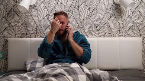 Bearded man in green or dark blue bathrobe talking by the phone and smoke Stock Footage 112830067