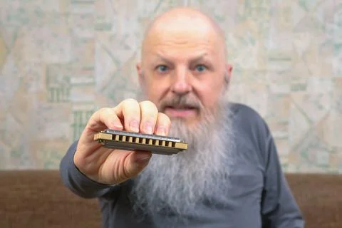 Bearded man with a harmonica in his hand. music and hobbies Stock Photos